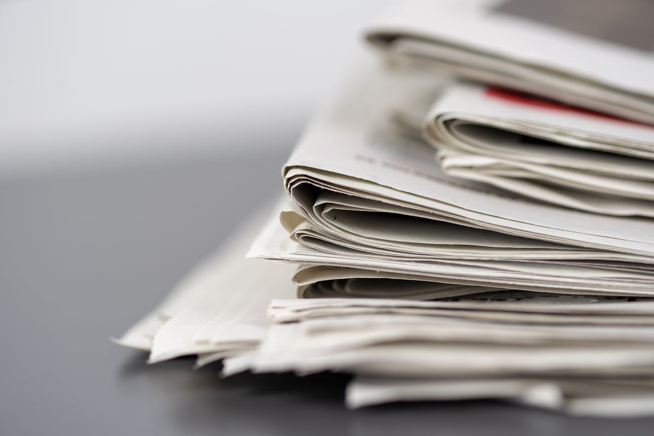 Close-up of stacked newspapers on a table, representing media and journalism.